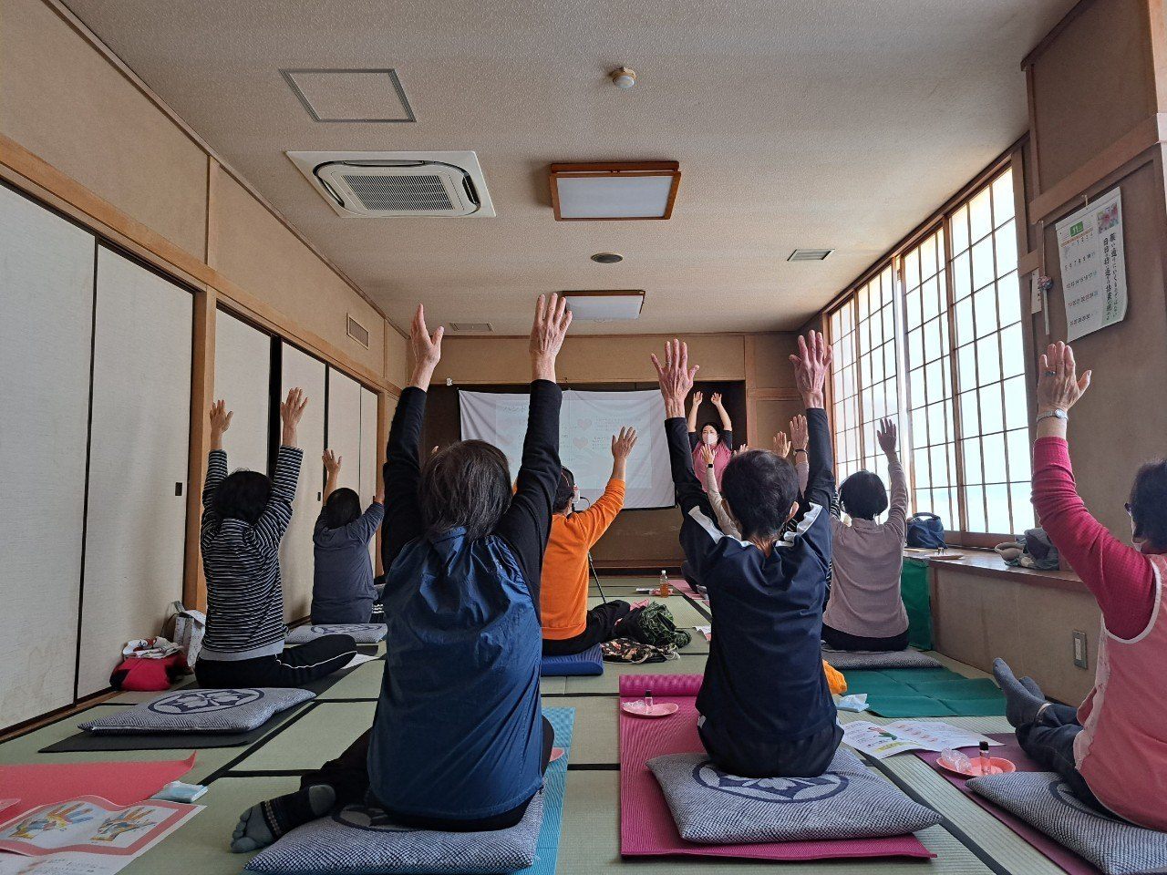 参加者が両手を挙げて体を動かすレッスン風景